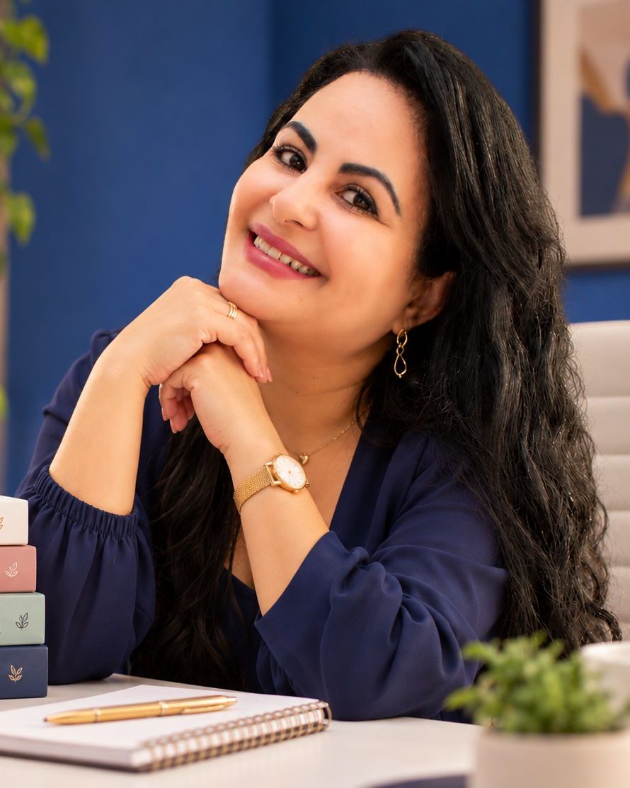 Edilma Vieira sorrindo em sua mesa de trabalho, com livros de psicologia e plantas ao fundo